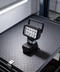 ABS Flood Light 15 LEDs Compatible with 18V Li-Ion Packs on a metal workbench, showcasing its sturdy design and functionality.