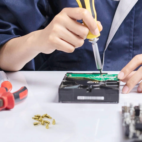 Technician using a screwdriver on a circuit board with Hardcore Heavy Duty M3 Hex Brass Standoff Spacers 10 Piece Set in view.