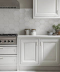 White kitchen cabinets with hexagonal tile backsplash and brushed nickel cabinet handles.