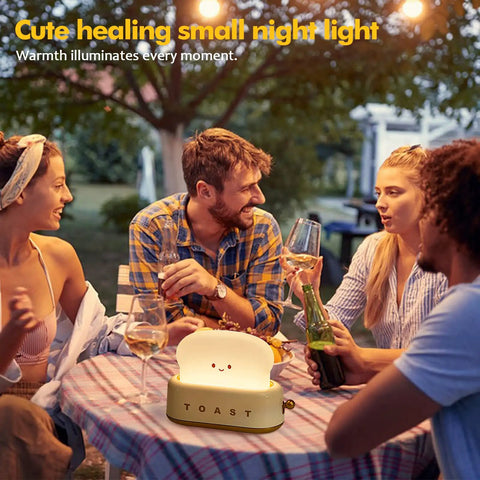Group enjoying outdoor dinner with Toaster Shaped LED Table Lamp With Rechargeable Battery Nightstand Light creating cozy atmosphere.