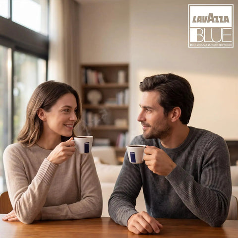 Man and woman enjoying coffee from Lavazza Blue cups at home, with warm interior setting and branded logo in view.
