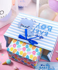 Blue Dinosaur Baby Boy Gift Bag with Tissue Paper and Greeting Card displayed open with colorful design, ribbon handles visible.