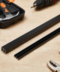 Black Aluminum Sliding Door Track Set For Four Foot Installations No Fuss DIY Friendly For One Quarter Inch Panels Closet Glass Doors Cabinets And Windows Durable Aluminum Alloy Metal Sliding Track Easy To Cut And Install on a workbench with tools.