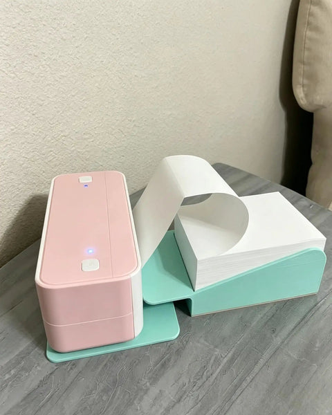 Keep Your Packing Game Strong With This Compact And Efficient Slick Thermal Printer Stand That Makes Feeding Fan Fold Shipping Labels A Breeze All Day Long showing a pink thermal printer with fan fold labels.