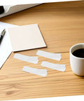 100 Pack Double Sided Hook And Loop Strips With White Pet Film Backing 2.5x10cm on a wooden desk with coffee cup.