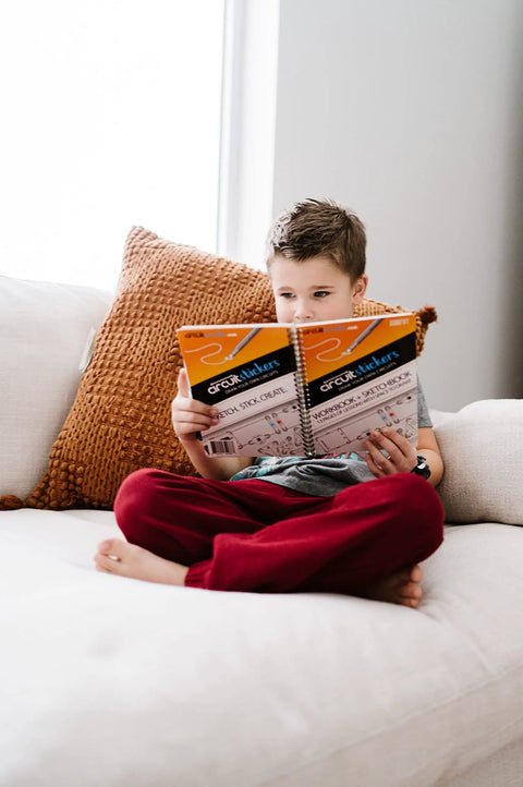 Child reading instructive workbook from Draw Circuits With Conductive Ink Pen Kit, 11 Electronic Sticker Modules, And A 27 Lesson Workbook