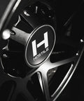 Close-up of 22X12 Satin Black Truck Wheels With 6X135 Bolt Pattern And Minus Forty Four Offset aggressive rims showcasing the logo.