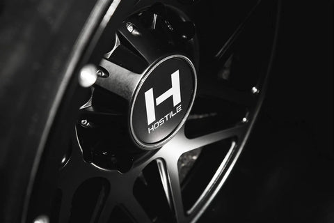 Close-up of 22X12 Satin Black Truck Wheels With 6X135 Bolt Pattern And Minus Forty Four Offset aggressive rims showcasing the logo.