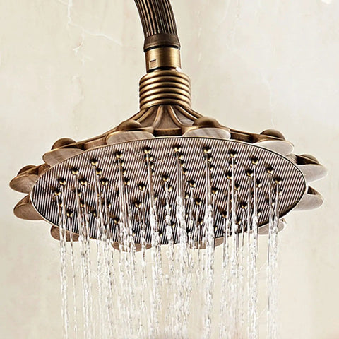 Antique Brass Exposed Shower System with Tub Spout 90° Rotating shower head with intricate pattern and water flow.