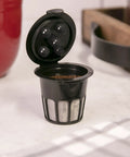 Cafe Supreme Reusable Coffee Filter Pod For Keurig Brewers So You Brew Like A Boss With Stainless Steel Mesh BPA Free Large 14.5g Capacity Easy To Clean Eco Friendly Alternative To Disposable Pods open on counter