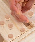 Hand placing 50 Pack DIY Wooden Hole Caps and Pocket Hole Plugs Hardwood Wood Plugs for Cabinets on wooden surface