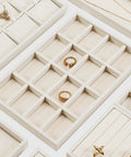 Totally Sweet Beige Linen Jewelry Display Tray With Sixteen Grid Slots For Rings Necklaces And Bracelets Ultra Soft Fabric Organizer showcasing individual compartments filled with rings.