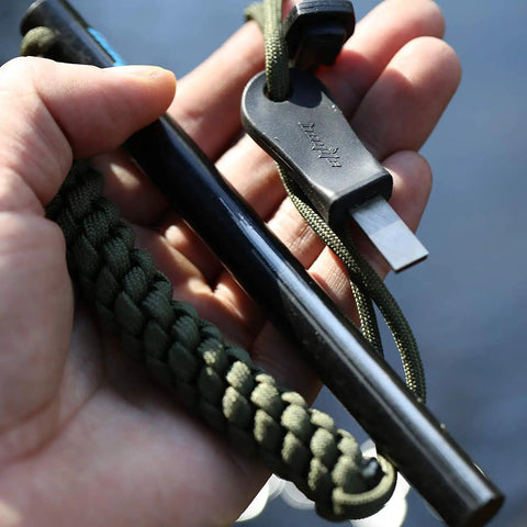Hand holding Survival Fire Starter Kit With Drilled Ferrocerium Rod Half Inch By Six Inch Striker Pro Striker Paracord Lanyard