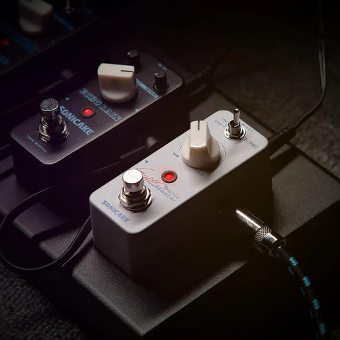 Close-up of Clean Boost Pedal With Buffer 0-12dB Gain Mini Pure Boost Guitar And Bass Effects Pedal With On Off Switch And Red LED Indicator Bypass When Off 9V Center Negative Power Compatible Gigs Ready, illuminated on pedalboard.