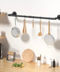 Built Like A Tank Wall Mounted Clothes Rack 3 Pack Black Industrial Pipe Garment Rail with kitchen utensils hanging.