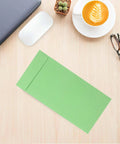 60 Pack Green Kraft Paper Coin Envelopes Self Seal With Double Adhesive on a desk with coffee and glasses