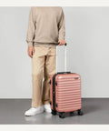 Person holding Hardside Carry-On Luggage 21 Inch With Multi-Directional Wheels Expandable Up To 25 Percent More Space Scratch-Resistant Surface Rose Gold Durable Travel Case For 1 To 5 Day Trips