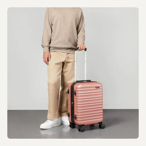 Person holding Hardside Carry-On Luggage 21 Inch With Multi-Directional Wheels Expandable Up To 25 Percent More Space Scratch-Resistant Surface Rose Gold Durable Travel Case For 1 To 5 Day Trips