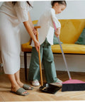 Heavy Duty Pink Broom With Extended Handle sweeps indoors, shown in use by a child for cleaning dust off the floor.