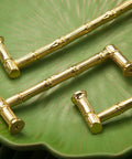 Gold Brass Bamboo Shape Cabinet Handles Set, Antique Brushed Copper Finish, displayed on a green surface