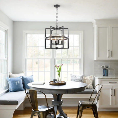 Kitchen interior with round table, metal chairs, and cage-style pendant light hanging above in a bright space.