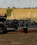 Person using ATV with 62 Inch Agricultural Landscape Rake With Tipper Latch And Spring Steel Tines for clearing field debris.