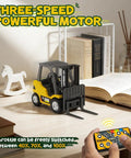 Mini RC Forklift 1 to 64 Scale Alloy Toy with App Programmable Path and Bluetooth Remote Control on desk with remote and books