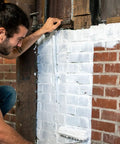 Man applying Block And Wall Liquid Rubber Waterproofer Pro Grade Multi Purpose Coating And Sealant For Concrete Walls And Foundations 1 Gallon White Made In USA Waterproof Basement Sealer on a brick wall