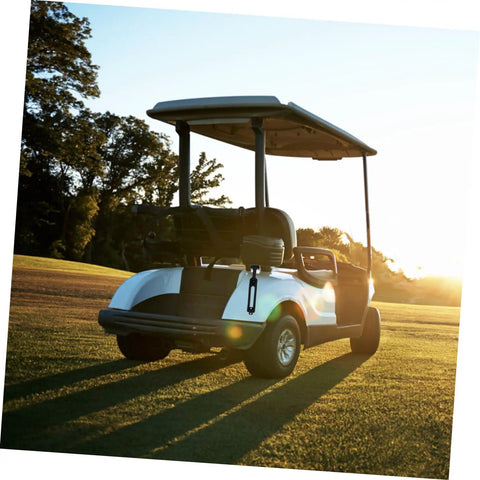 Golf cart on green field at sunset