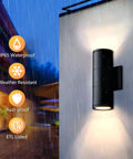 Modern Outdoor Wall Lights Up and Down Cylinder Sconce Matte Black Pack of 2 Waterproof Exterior Fixtures for Porch Patio Garage Front Door No Fuss Mount Easy Install Durable All Weather Lighting mounted on wall, with light shining up and down in rain.