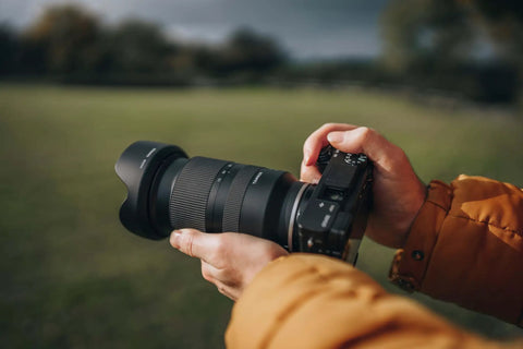 Person holding 17-70mm F2.8 Di III A VC RXD Lens For Sony E APS-C Mirrorless Cameras With Built-In Vibration Compensation And Fast Autofocus