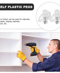 Man installing 100 Pack Plastic Shelf Pegs Set With Self Locking Design in white cabinet with drill