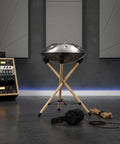Heavy Duty Beech Wood Drum Rack Adjustable Percussion Stand For Conga And Steel Drums Foldable Tripod Rig with a hang drum and accessories in a studio.