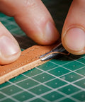 Close-up of 7 In 1 Pro Grade Leather Groover Tool trimming leather on a cutting mat, showcasing precise DIY leathercraft cutting.