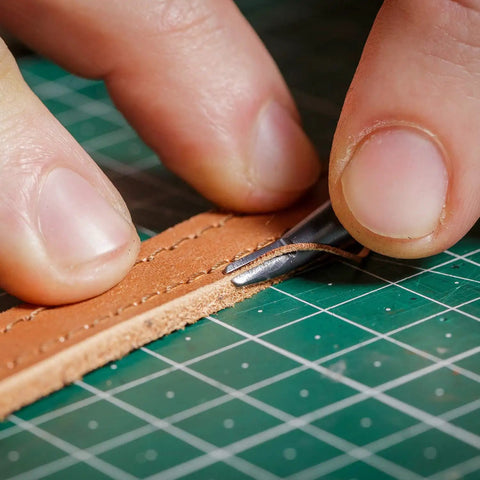 Close-up of 7 In 1 Pro Grade Leather Groover Tool trimming leather on a cutting mat, showcasing precise DIY leathercraft cutting.