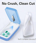 Open blue pill cutter with removable silicone liner, showing pills inside, emphasizing no crush clean cut feature.