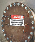 Permit Required Confined Space Danger Sign 10X7 Inches OSHA Compliant Wall Plate mounted on a metal surface with bolts.