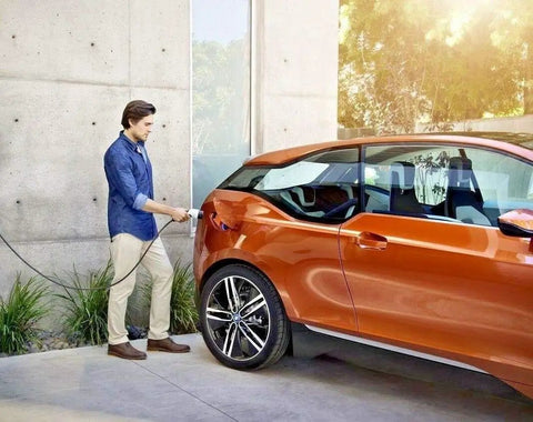 Man using Portable Type 1 And Type 2 EV Charger 10A With UK Plug CEE Plug And European Schuko Plug For US Type 1 J1772 And European Cars On The Go 240V Level 2 Ready For Home Or Road Charging Station on orange electric car
