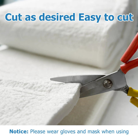Front view: White ceramic fiber insulation blanket, 24 x 16 x 1 in, being cut with red-handled scissors.