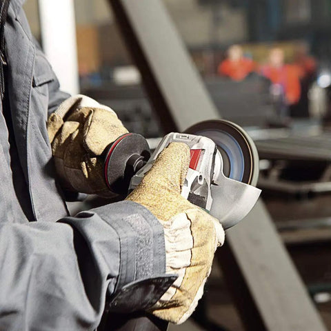 Worker using heavy duty 5 inch angle grinder with 13.5 amp motor and 11000 RPM electronic speed stabilization Non Locking Paddle Switch