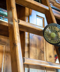 5 Inch Battery Powered Clip On Fan With Clamp 2 Pack attached to a wooden ladder in a library setting for hands-free cooling.