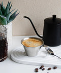 Go-To Stainless Steel Espresso Cup With Handle 3.4oz 100ml on tray near coffee pot, wide spout for home barista