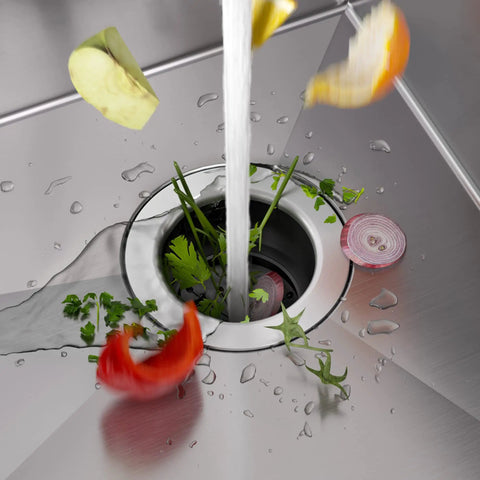 Vegetable scraps entering stainless steel WasteGuard Beefy 3/4 HP Ultra Quiet Garbage Disposal with Quick Connect in sink.