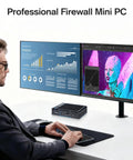 Person using a keyboard with the Rock Solid Fanless Router Firewall Mini PC on a desk with dual monitors displaying graphs and images.