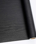 Close-up of rolled 24 Inch By 196 Inch Black Wood Peel And Stick Wallpaper For Furniture Self Adhesive Film Durable Finish.