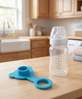 Blue Silicone Bathtub Drain Plug Stopper for Easy Removal next to clear baby bottle on a wooden kitchen countertop.
