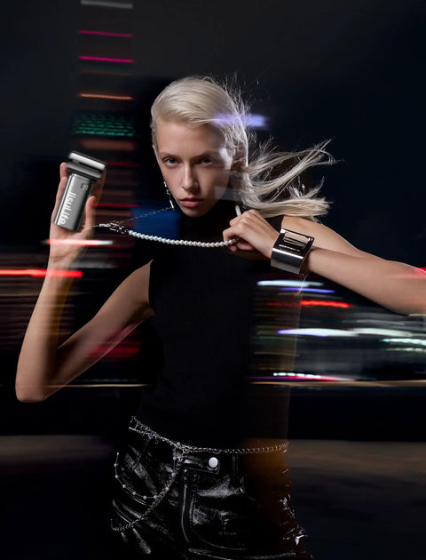 Model holding a portable handheld turbo fan with high speed air, wearing a black top in an urban night setting.