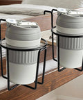 Stainless Steel Cup Holder Stand for Kitchen Counter and Outdoor Adventures with two gray cups on wooden surface.