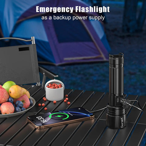 Ultra Bright LED Flashlight With 50,000 Lumens And A 3937 Foot Beam, USB C Rechargeable next to phone and fruit, camping tent background