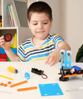 Child assembling Five In One Robotics Kit For Kids Aged 8 To 12 Build Obstacle Avoidance Robot Solar Powered Car Tank Wind Powered Car And Glider With Hands On STEM Toys For Boys 8 10 12 14 Year Old Gifts with colorful parts on a table.